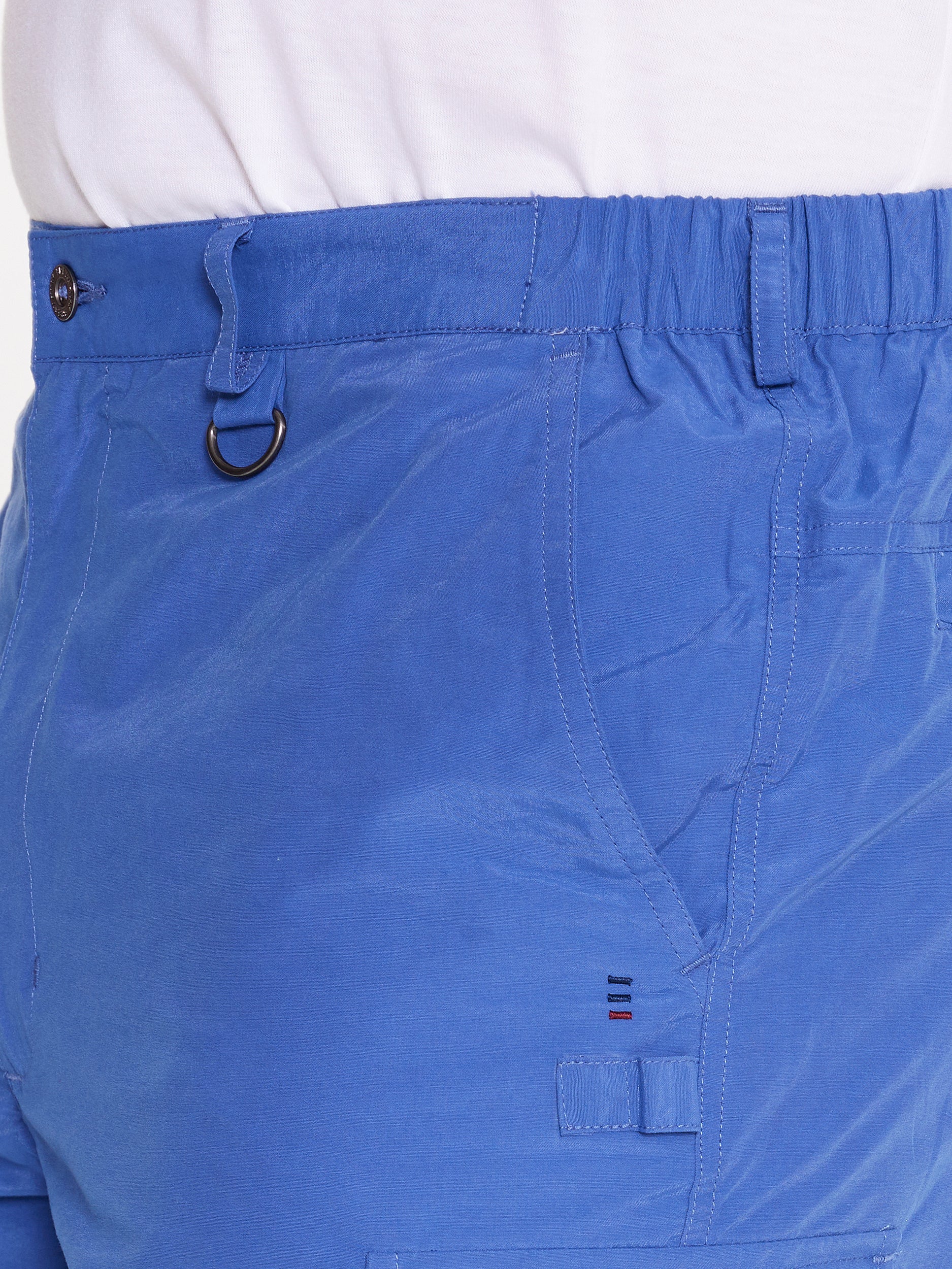 Close up side image of model wearing the mens Woodbury Short in blue. Short has button fly, belt loops, elastic waist, and slanted pockets.
