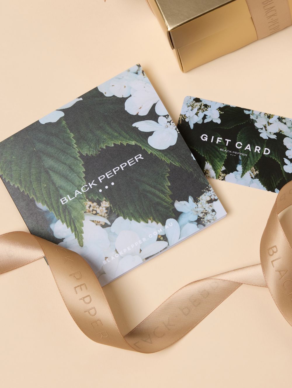 Gift card with black pepper design and gold box on beige surface